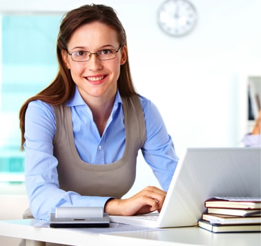Professional woman at desk smiling with laptop